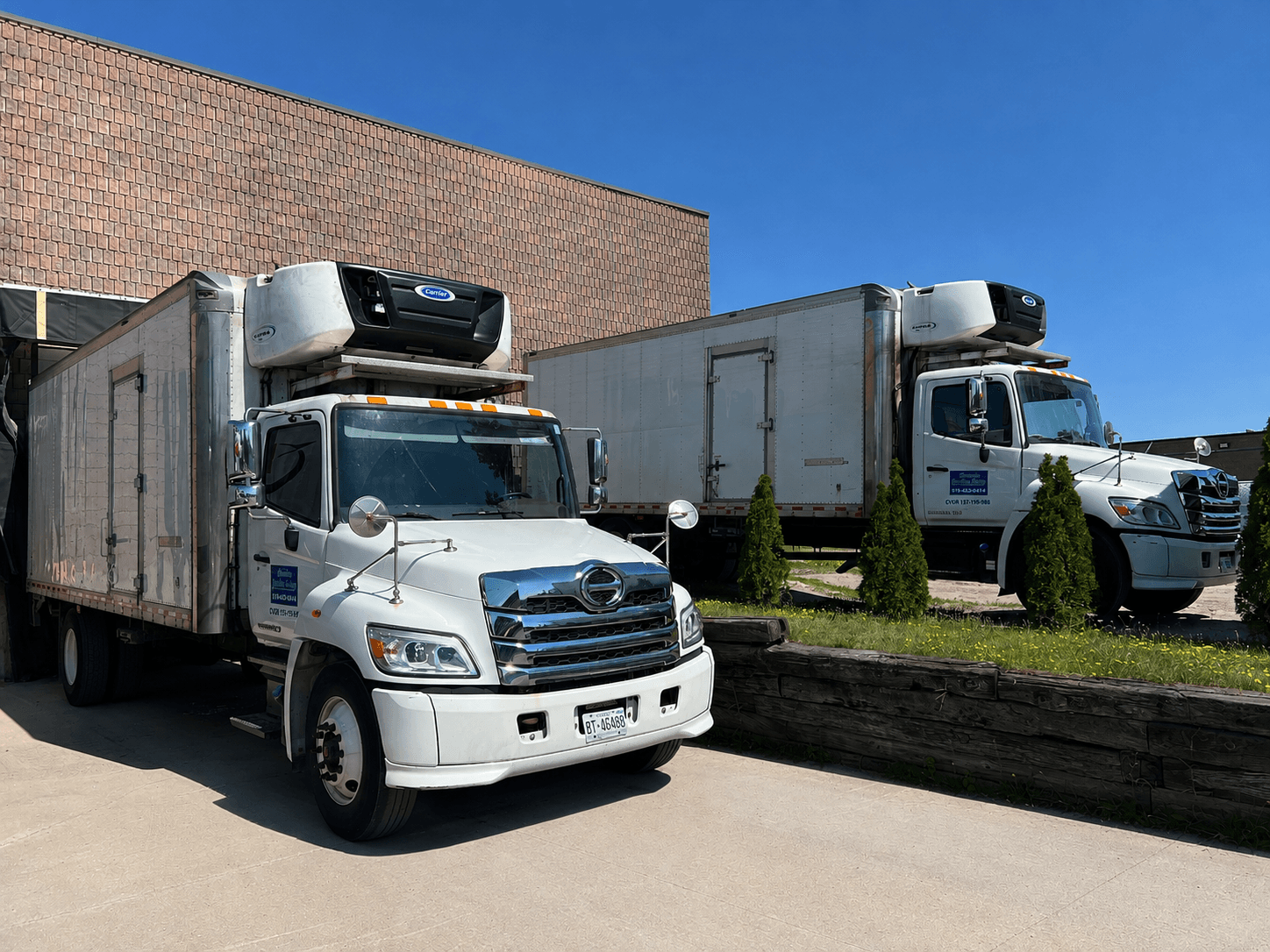 Two London Quality Dairy delivery trucks parked side by side outside the company's facility.